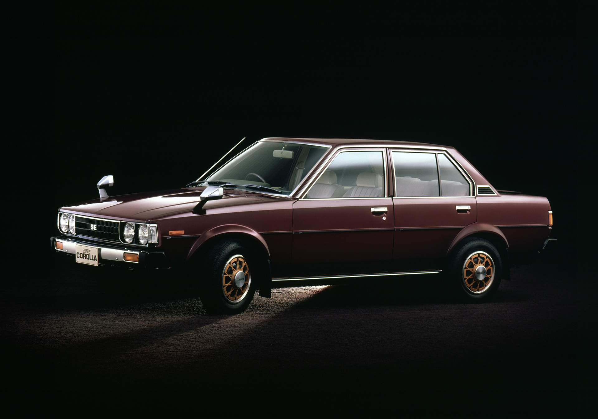 Mørkerød Toyota Corolla fra 1979-generationen fotograferet fra siden.