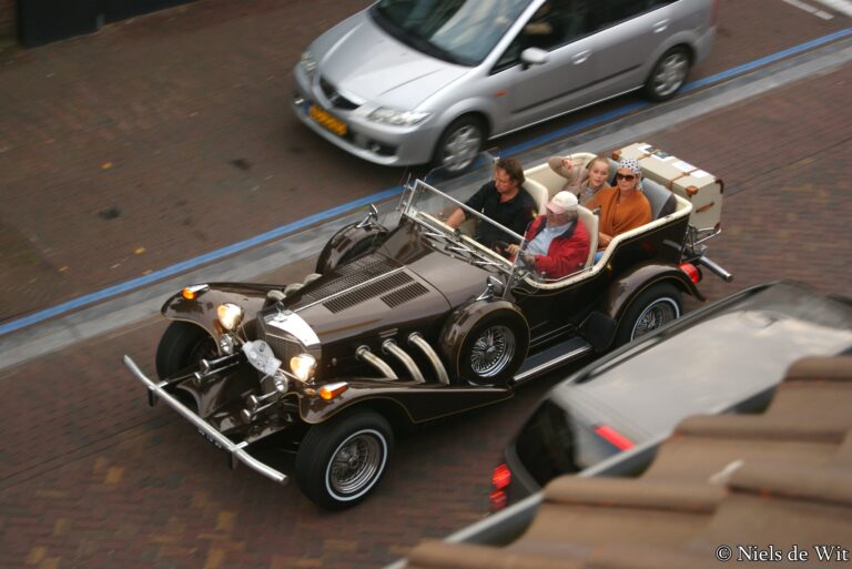 Excalibur Phaeton Series III fra 1976 med lang motorhjelm og fritstående forlygter ved et biltræf.